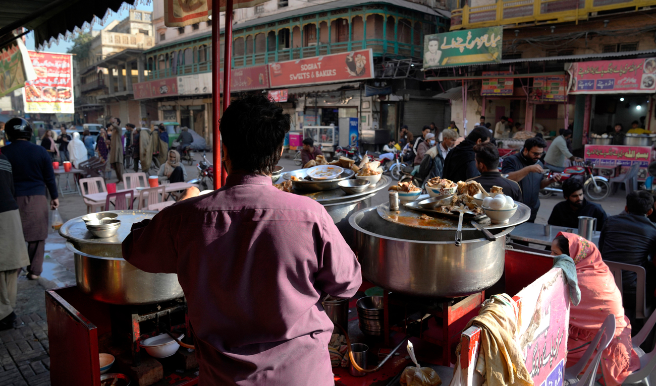 People eat breakfast at a famous food street of Gawalmandi, an old area of Lahore, Pakistan, Sunday, Dec. 11, 2022. Gawalmandi is the city's neighborhood crammed with people, vehicles, animals, and food stalls. (Photo courtesy: AP)