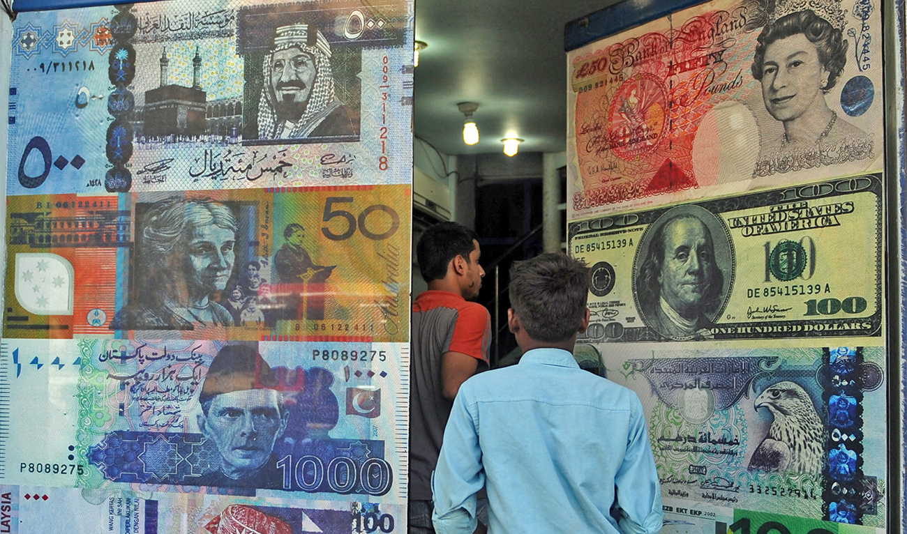 Pakistani customers enter a foreign currency exchange shop in Karachi, Pakistan, on October 14, 2010. (AFP/File)