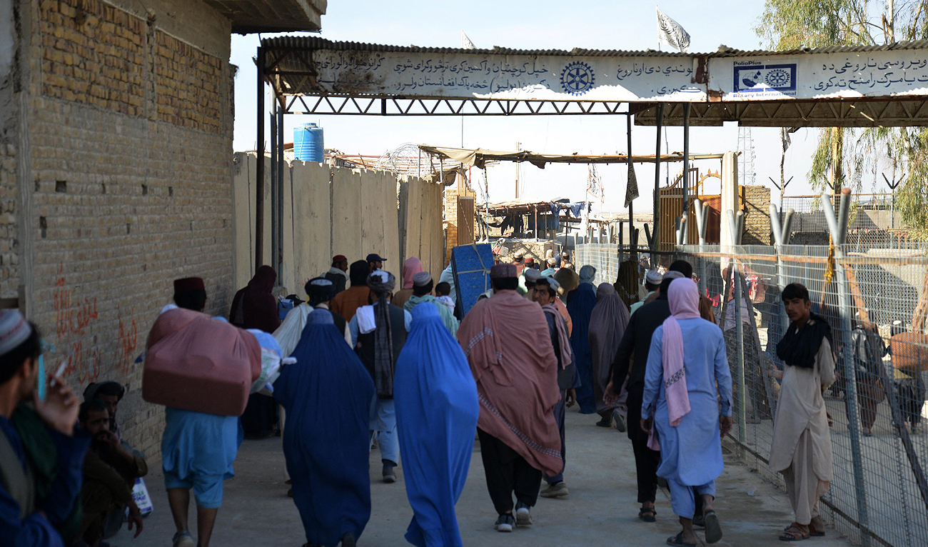 In this picture taken on November 21, 2022, Afghans walk along a fenced corridor as they cross into Pakistan at the Afghanistan-Pakistan border in Spin Boldak. (Photo courtesy: AFP)