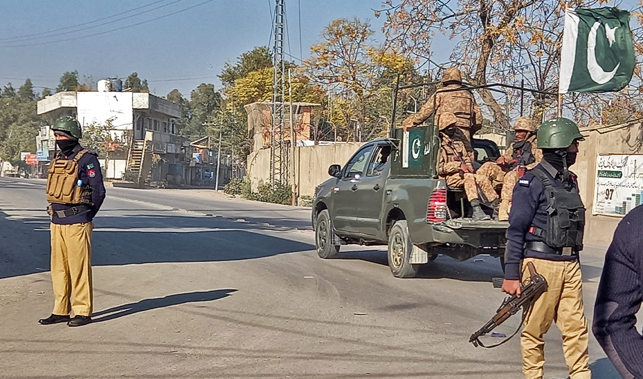 An Army vehicle patrols, past police officers stand guard along a road, near cantonment area in Bannu, Pakistan on December 21, 2022. (REUTERS)