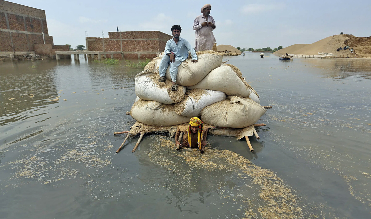 Flood victims from monsoon rain use a makeshift barge to carry hay for cattle, in Jaffarabad, a district of Pakistan's southwestern Balochistan province, on September 5, 2022. (AP)