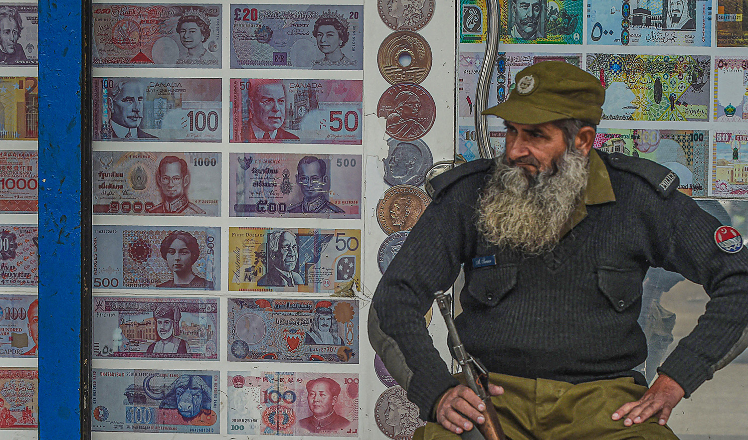 A security guard sits outside the currency exchange shop in Lahore, Pakistan on January 3, 2018. (AFP/File)