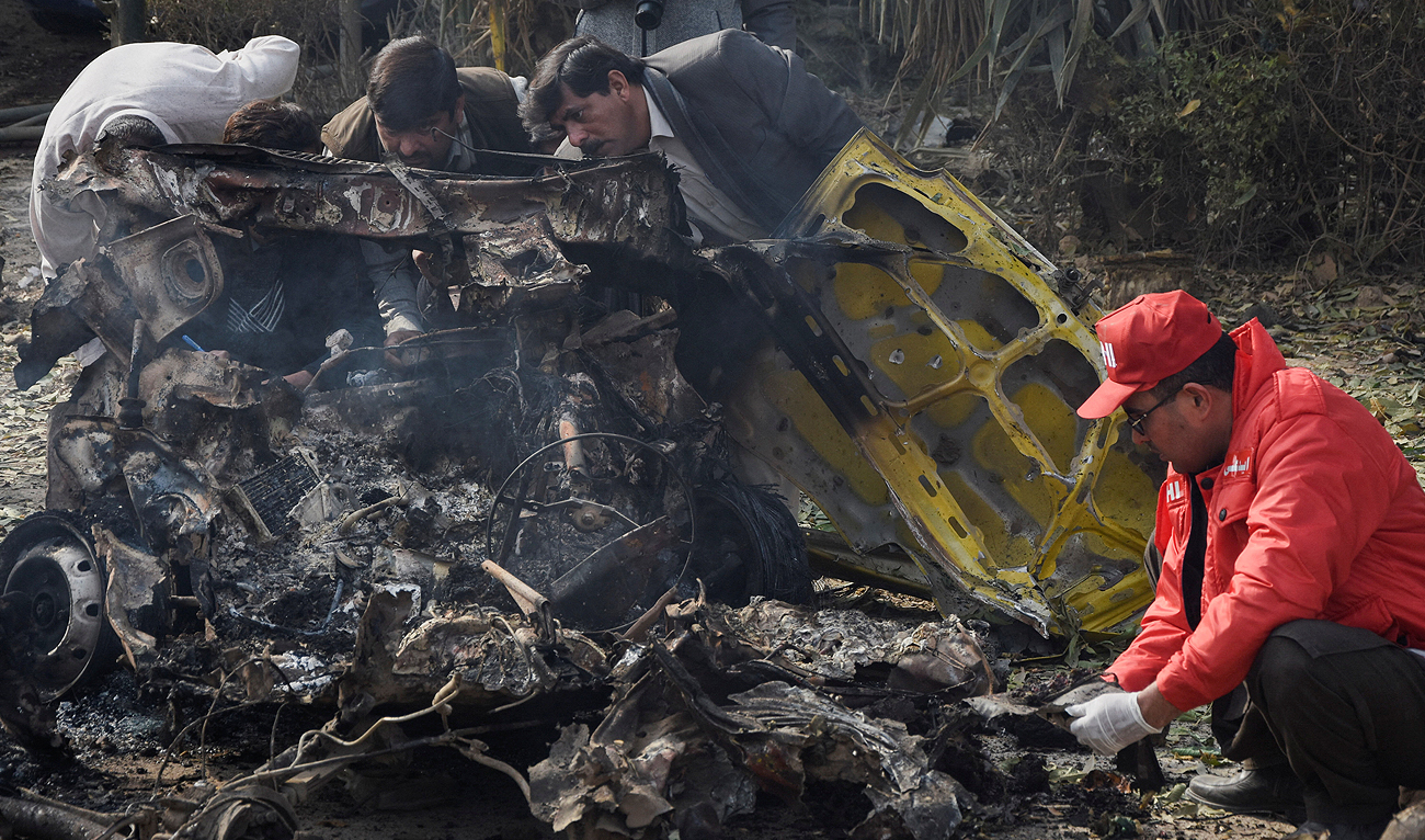 A rescue worker collects body parts while police officers investigate a wreckage at the site of a suicide car bombing in Islamabad, Pakistan December 23, 2022. (Photo courtesy: REUTERS)