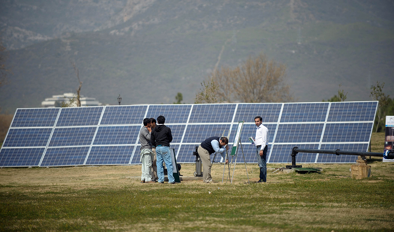 In this file photo taken on March 10, 2012, Pakistani company employees arrange solar panels for a marketing demonstration in a park in Islamabad. (Photo courtesy: AFP/File)