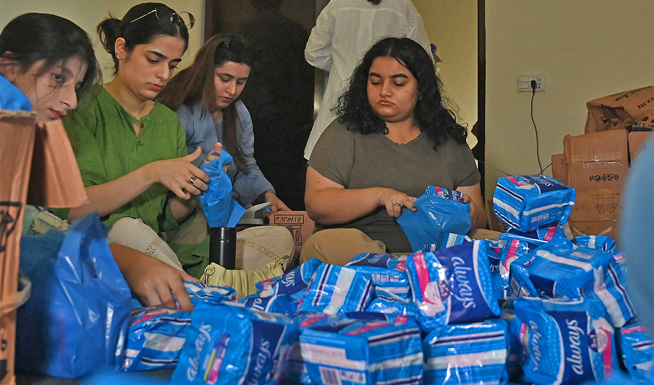 Members of a non-governmental organisation pack sanitary pads for women displaced by massive flooding in Lahore, Pakistan, on August 31, 2022. (AFP)