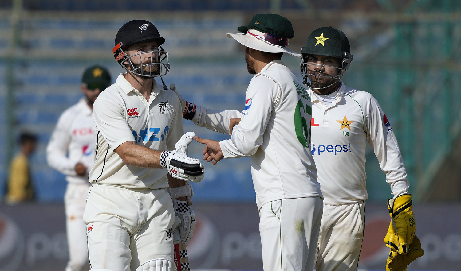New Zealand's Kane Williamson, who scores 200 runs not out, is congratulated by Pakistan's Agha Salman, center, and Sarfraz Ahmed, right, during the fourth day of first test cricket match between the two teams in Karachi, Pakistan, on December 29, 2022. (AP)