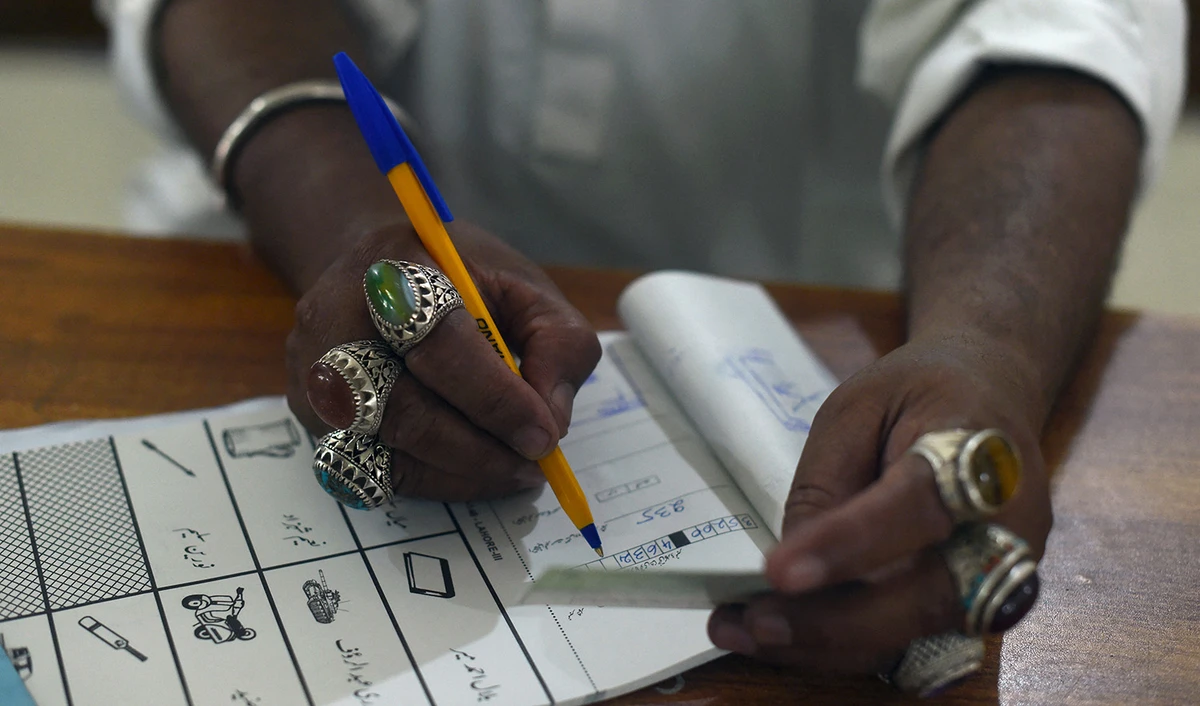 A election official man notes down information of an ID of a voter during Pakistan's general election at a polling station in Lahore on July 25, 2018. (AFP/File)