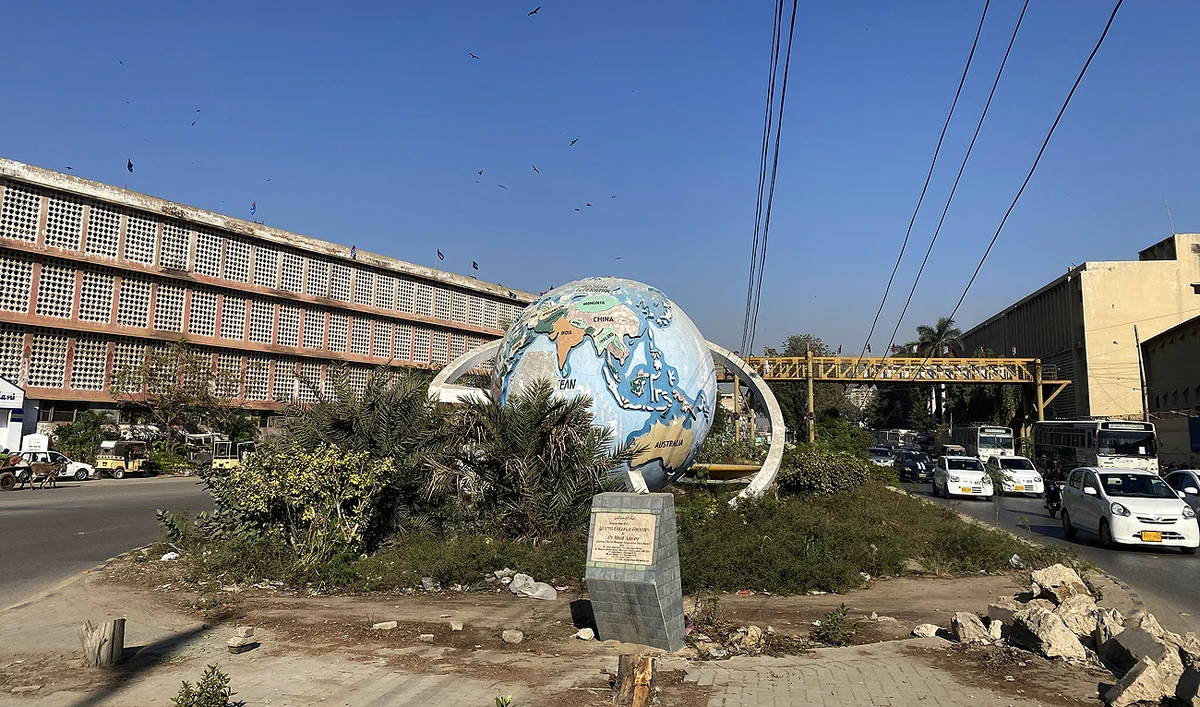 In this picture, taken on December 17, 2022, commuters pass by Karachi's iconic globe monument, situated at M.A. Jinnah Road in the Saddar area, which authorities plan to remove, making way for a mass transit project. (AN Photo)