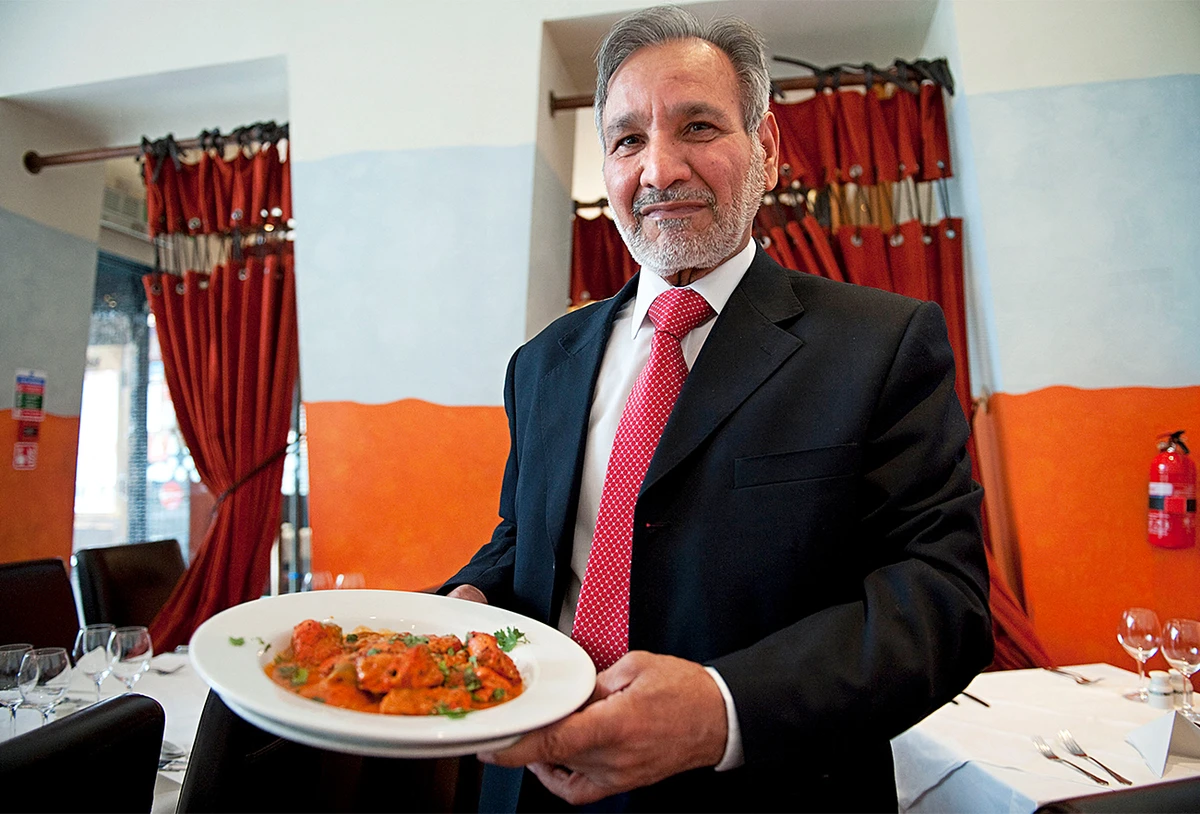 Ahmed Aslam Ali, the owner of the Shish Mahal restaurant in Glasgow, UK, holds a plate of Chicken Tikka Masala in his restaurant on July 29, 2009. (AFP)