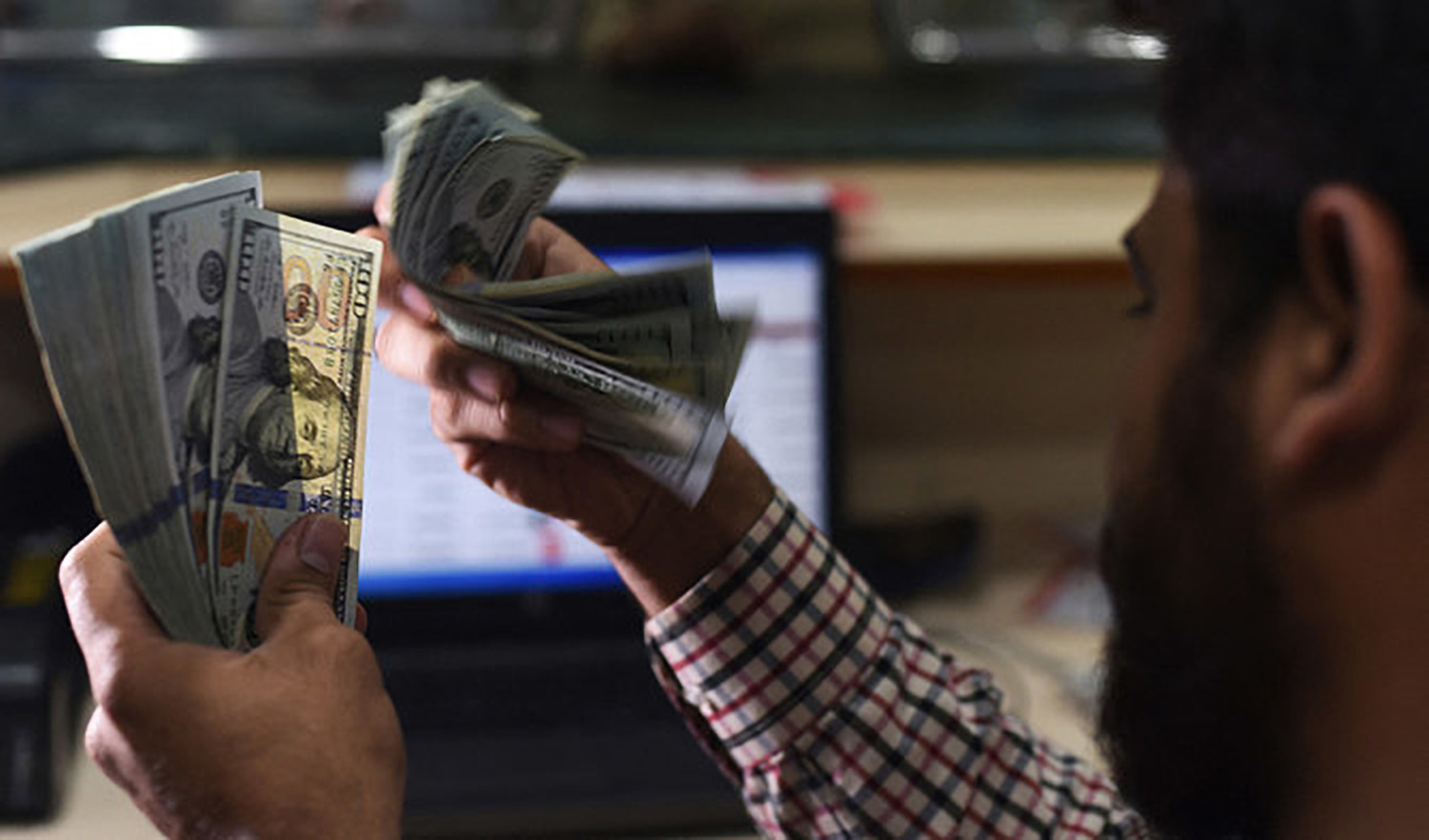 A Pakistani dealer counts US dollars at a currency exchange shop in Karachi, Pakistan, on October 9, 2018. (AFP/File)
