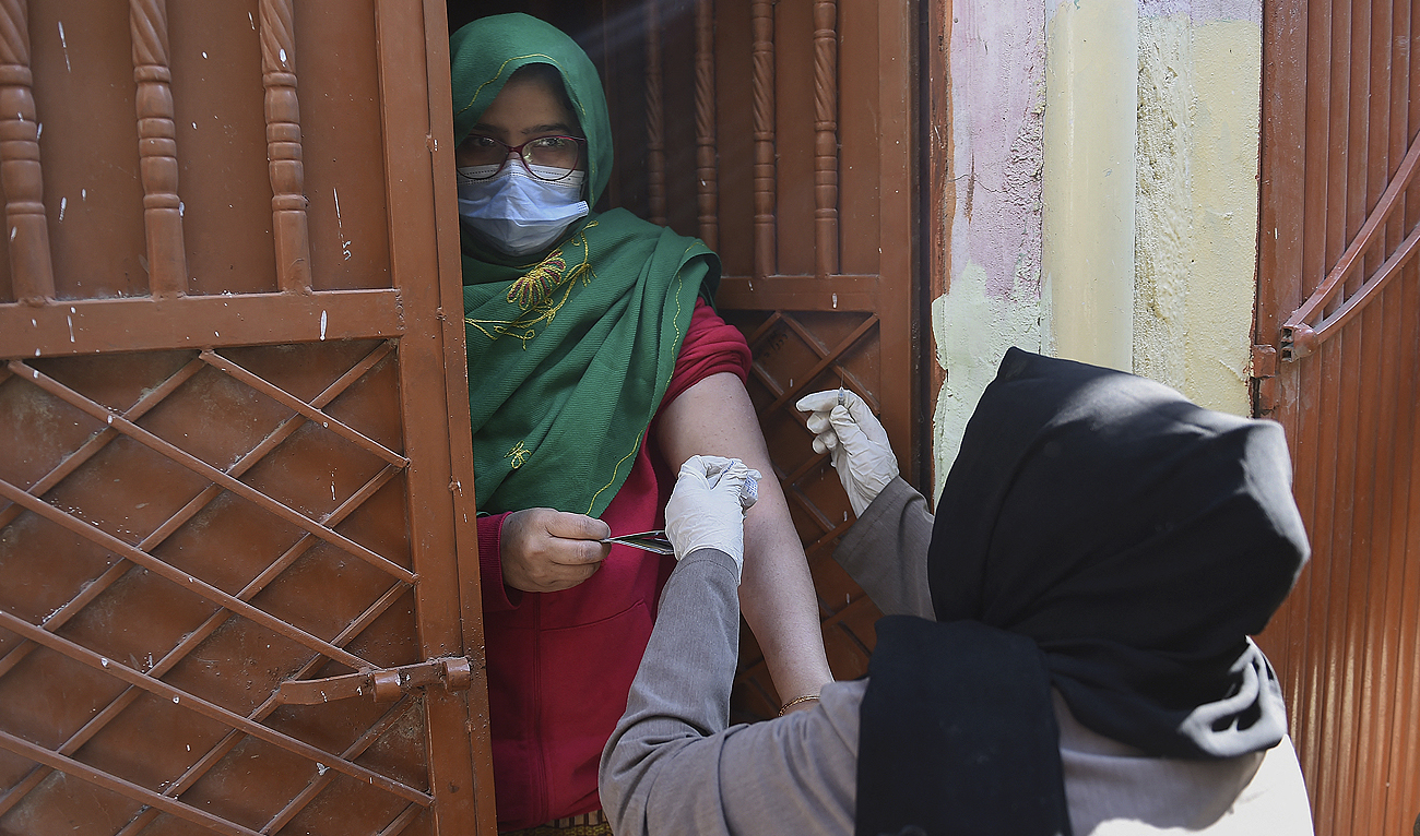 In this file photo taken on January 11, 2022, a health worker (R) inoculates a woman with a dose of the Covid-19 coronavirus PakVac vaccine during door to door vaccination in Karachi. (Photo courtesy: AFP/File)