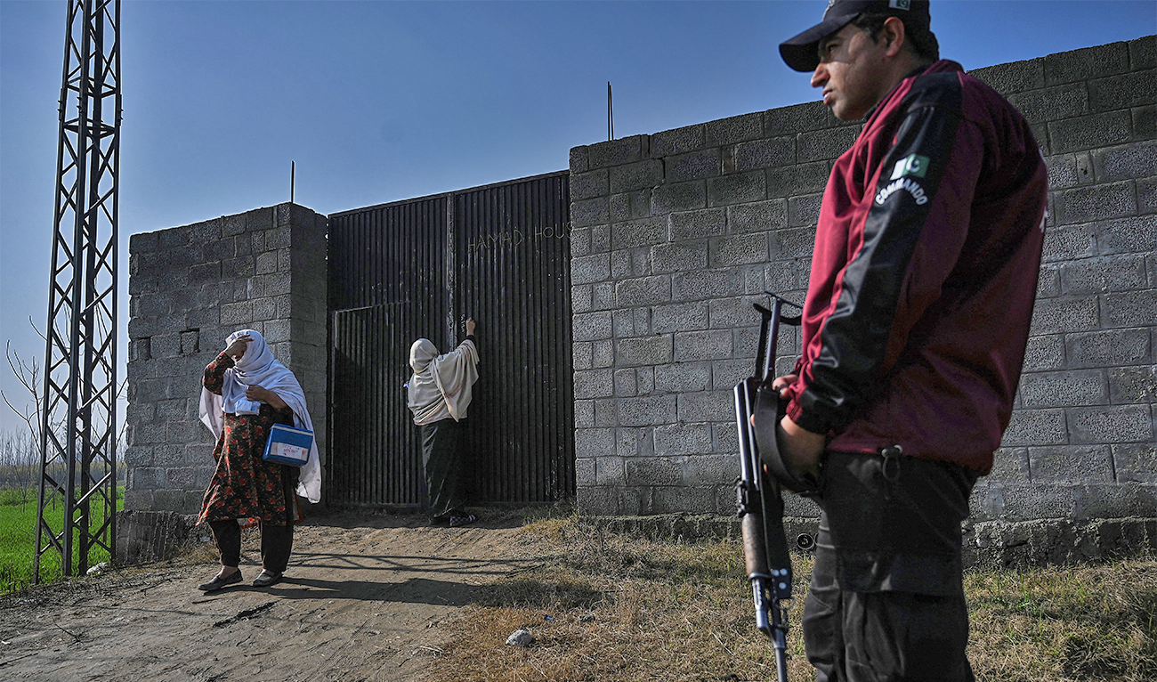 In this picture taken on January 24, 2022, a health worker marks a house after administering polio vaccine drops to children as a policeman (R) stands guard during a door-to-door polio vaccination campaign on the outskirts of Mardan, in the Pakistan's Khyber Pakhtunkhwa province. (AFP/File)