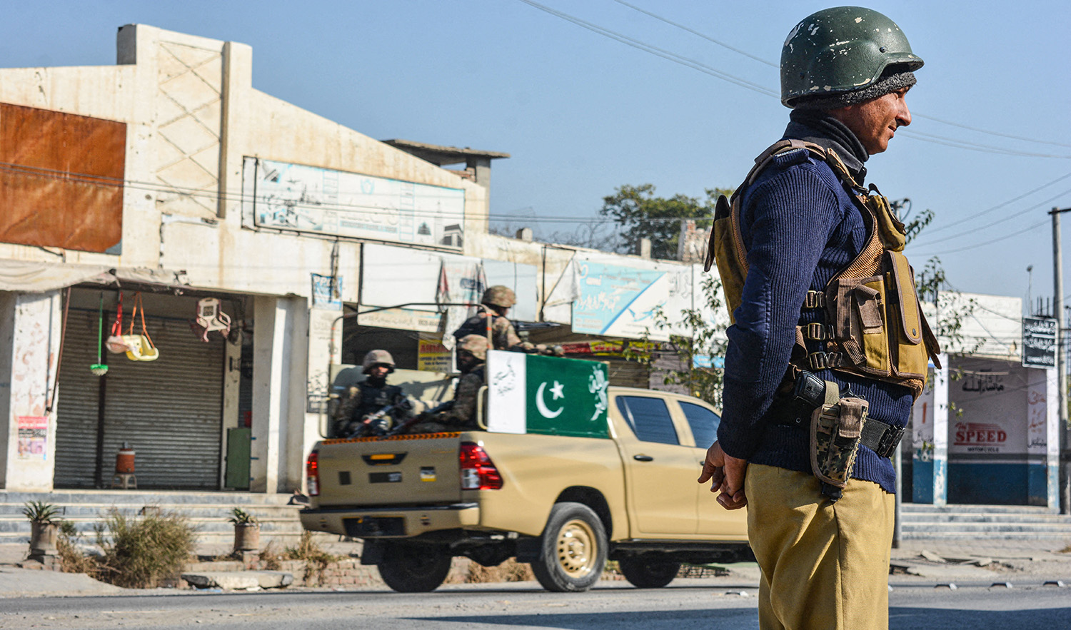 A policeman and army soldiers stand guard along a road in Bannu, Pakistan, on December 21, 2022. (AFP/File)
