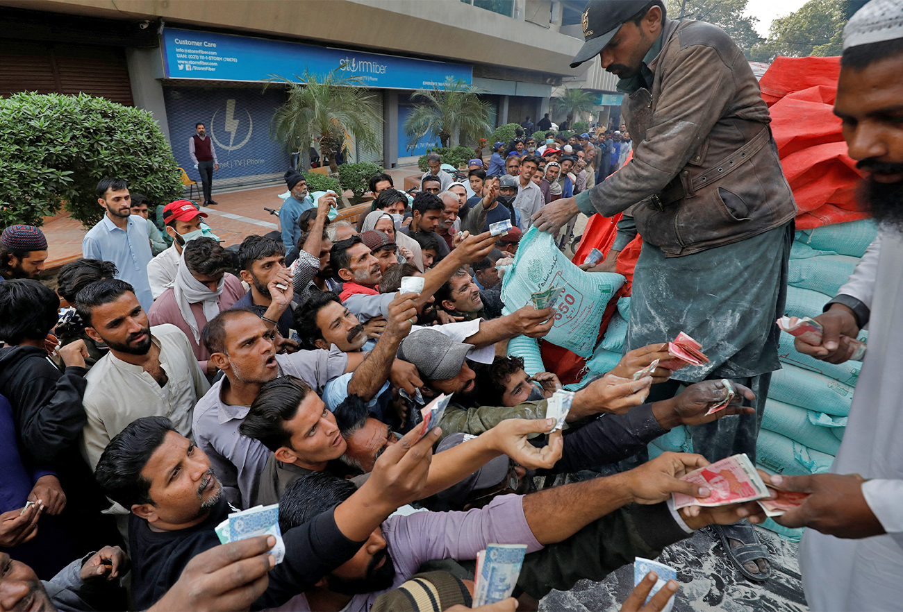 Men reach out to buy subsidised flour sacks from a truck in Karachi, Pakistan on January 10, 2023. (REUTERS)