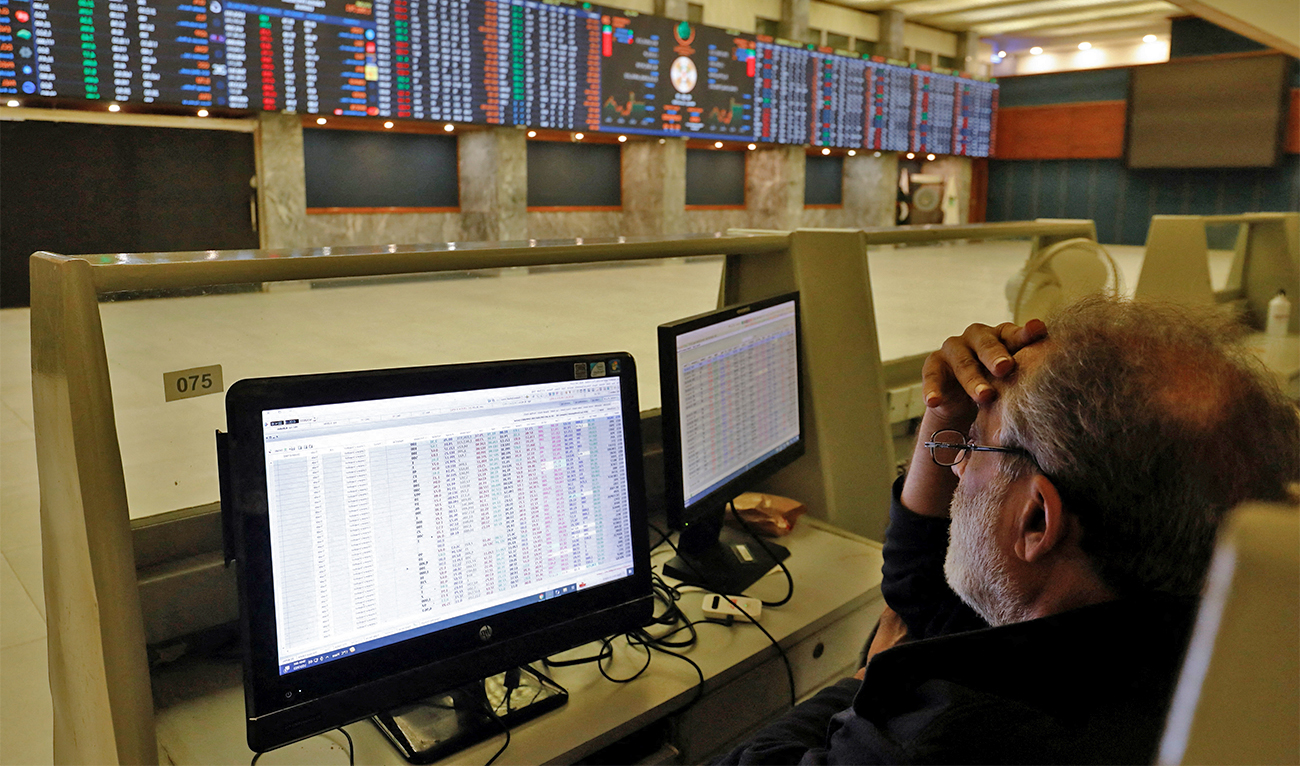 A stock broker monitors the share prices on computers, powered by the generator, in the hall of Pakistan Stock Exchange (PSX) during country-wide power breakdown in Karachi, Pakistan on January 23, 2023. (REUTER)