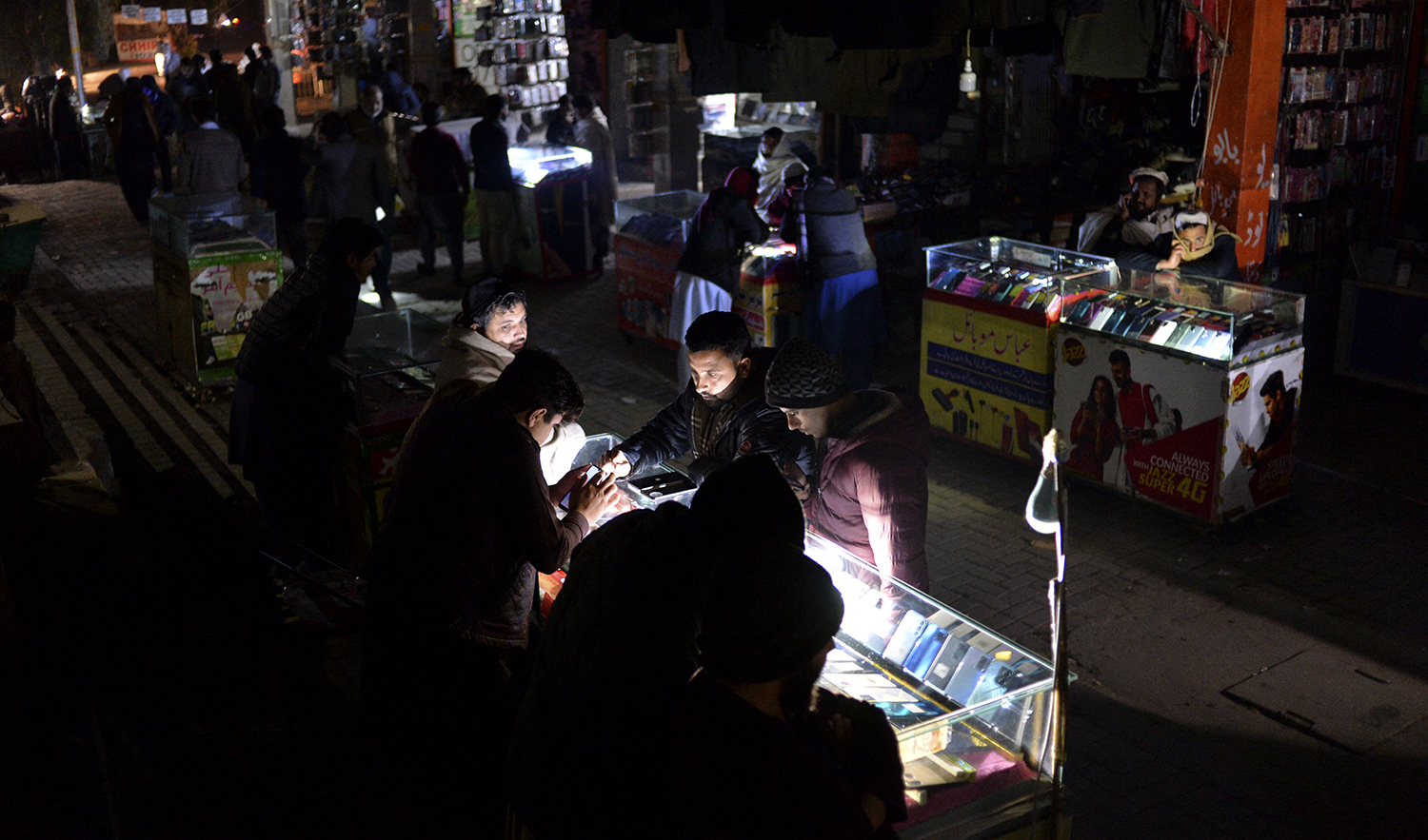 Shopkeepers sit at a market during a nationwide power outage, in Islamabad, Pakistan on January 23, 2023. (AFP)
