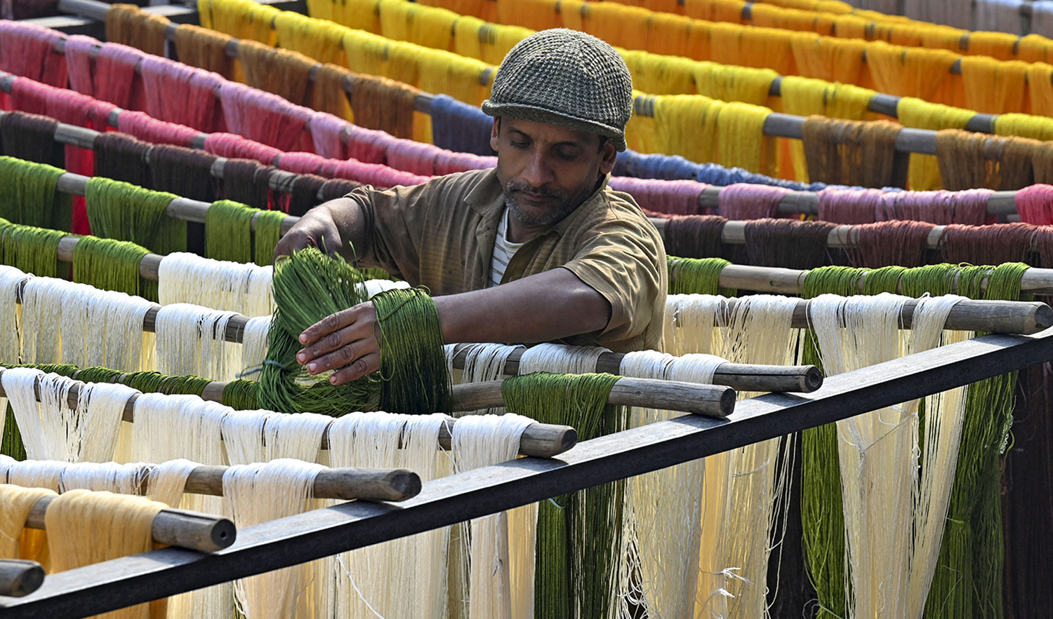 A worker dries thread after dyeing at a factory in Lahore, Pakistan on January 2, 2023. (AFP)