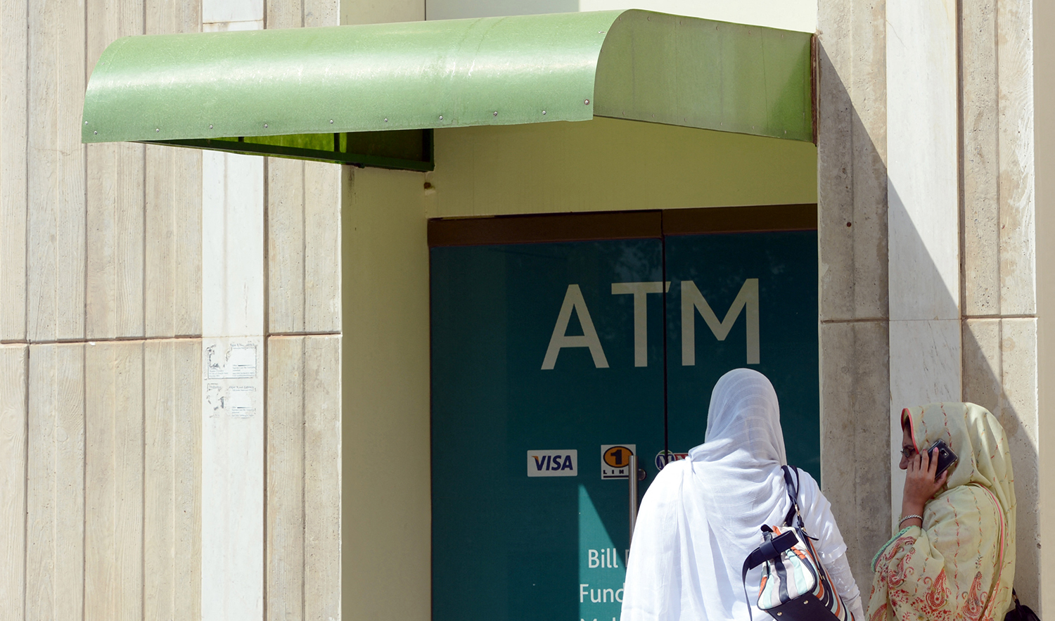 Pakistani women wait for their turn outside a bank Automated Teller Machine (ATM) in Islamabad on October 5, 2012. (AFP/File)