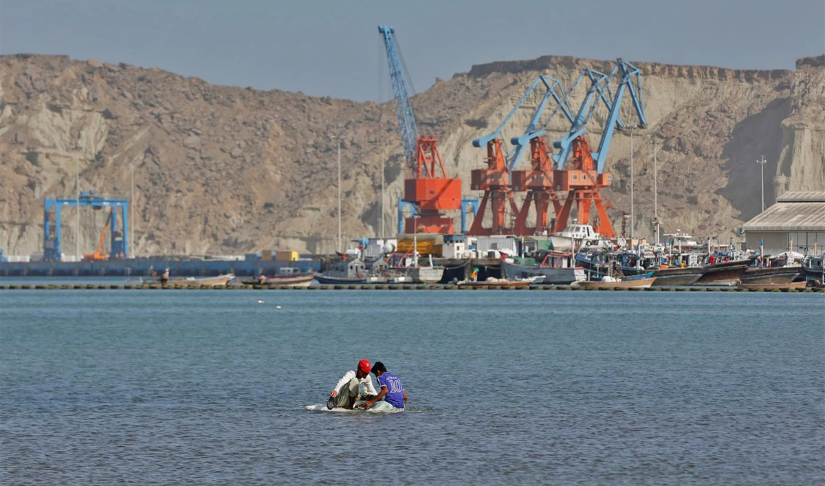 Boys sit on a piece of styrofoam sheet as they search for crabs in front of the Gwadar port in Pakistan on April 11, 2017. (Reuters)