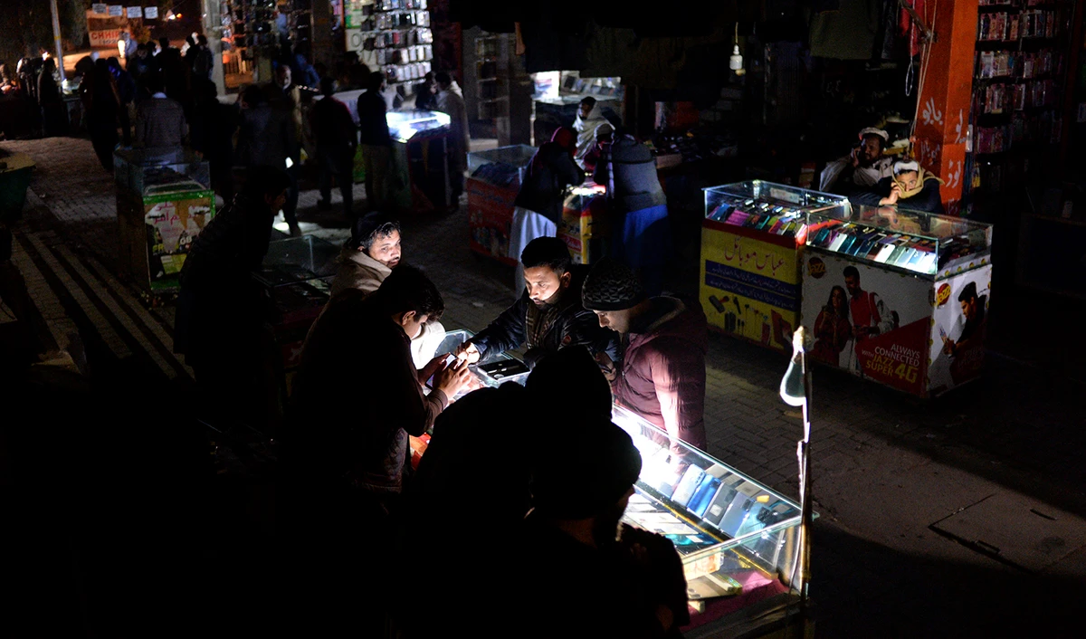 Shopkeepers sit at a market during a nationwide power outage, in Islamabad, Pakistan on January 23, 2023. (AFP)