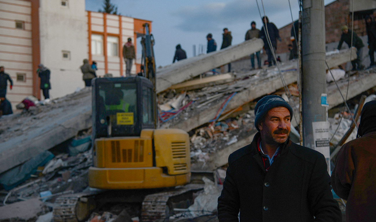 A photo taken on on February 8, 2023, shows a man looking on as residents and rescue personnel search for victims and survivors through the rubble of collapsed buildings in Adiyaman, two days after a 7,8-magnitude earthquake struck southeast Turkey. (Photo courtesy: AFP)