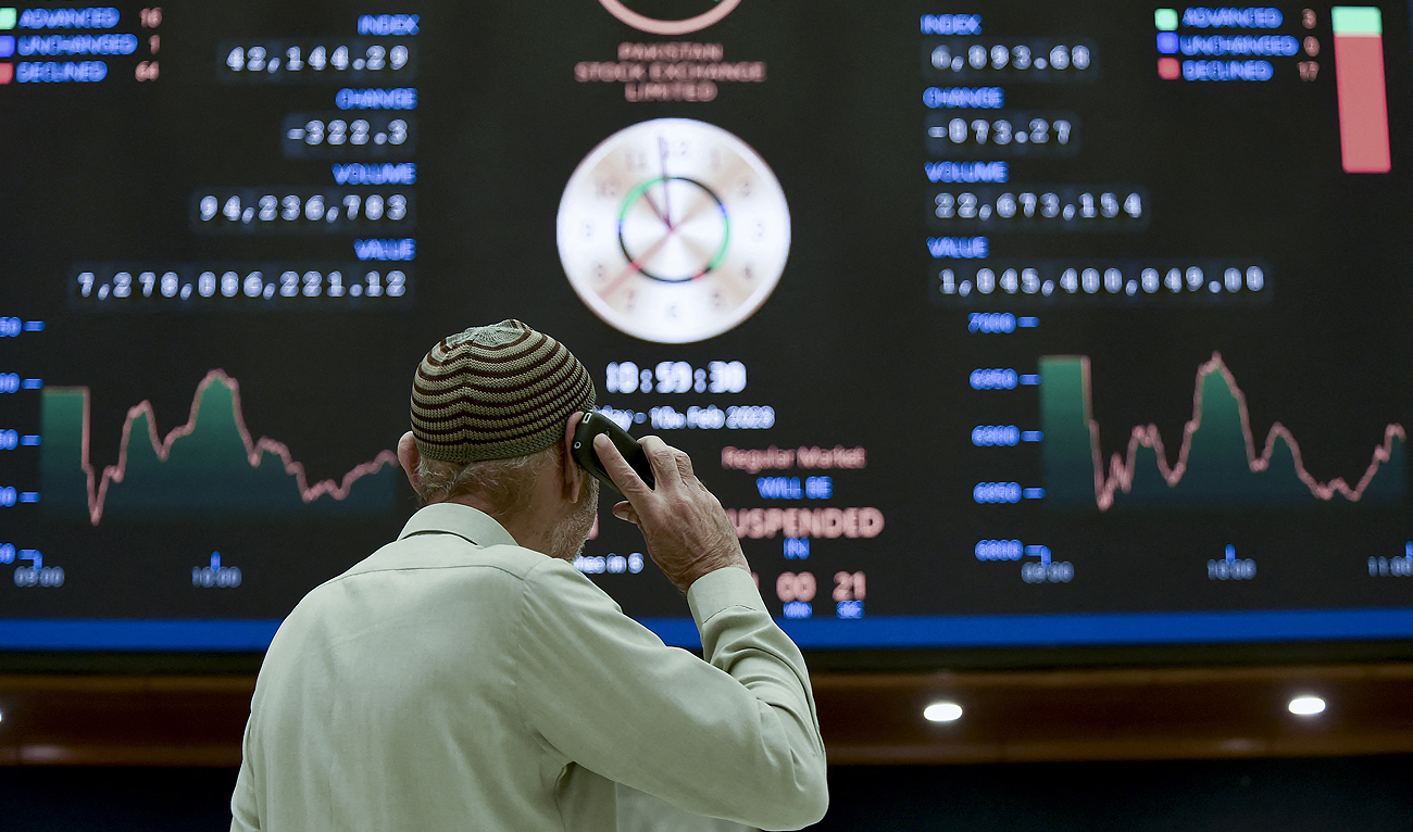 A broker talks on phone as he looks an index board showing the latest share prices at the Pakistan Stock Exchange in Karachi on February 10, 2023. (Photo courtesy: AFP)