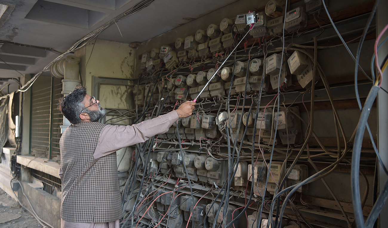 In this file photo taken on November 7, 2018, a Pakistani employee of the state-run Islamabad Electric Supply Company (IESCO), takes a meter reading with his smartphone at a commercial building in Islamabad. (Photo courtesy: AFP/File)