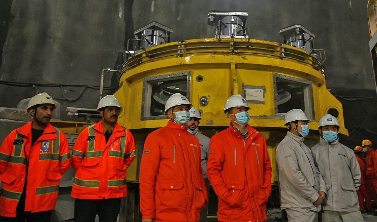 In this picture taken on February 7, 2022, Chinese engineers wearing hard hats watch during a media tour of the under-construction dam site in the Kaghan valley of Mansehra district. (AFP/File)