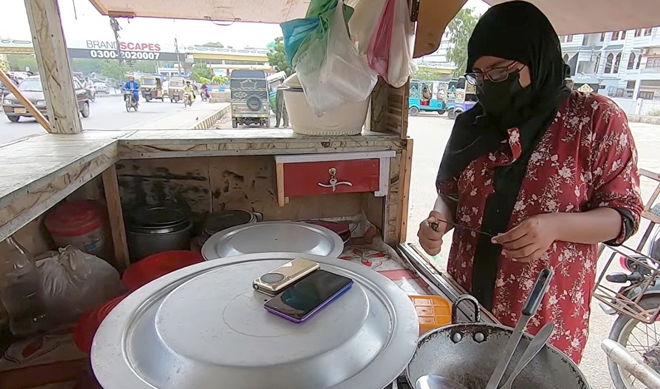 This photo, posted on July 3, 2022, shows Karachi-based entrepreneur Nazia popularly known as ‘Baji Daal Chawal Wali’ standby at her roadside kiosk in Karachi. (Photo courtesy: Chehra Digital)