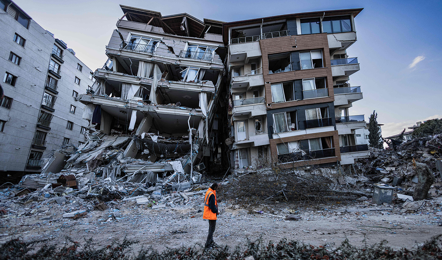 A rescue worker walks past partially collapsed buildings in Antakya, Turkey on February 19, 2023. (AFP)