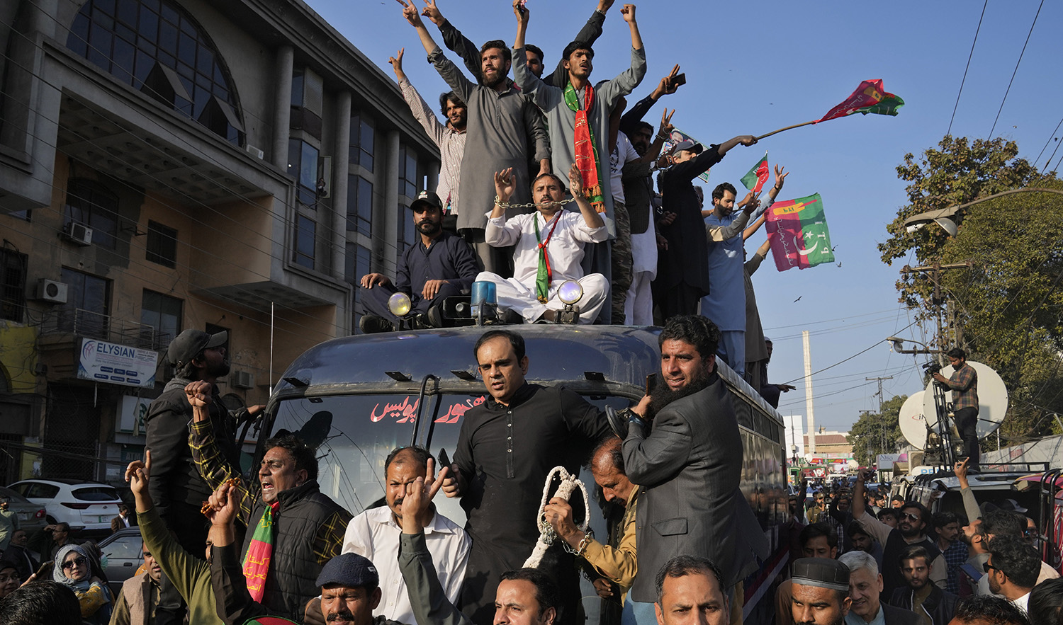 Supporters of Pakistan's former prime minister Imran Khan's 'Pakistan Tehreek-e-Insaf' party climb on a police van and chat ant government slogans during a rally, in Lahore, Pakistan, on February 22, 2023. (AP)