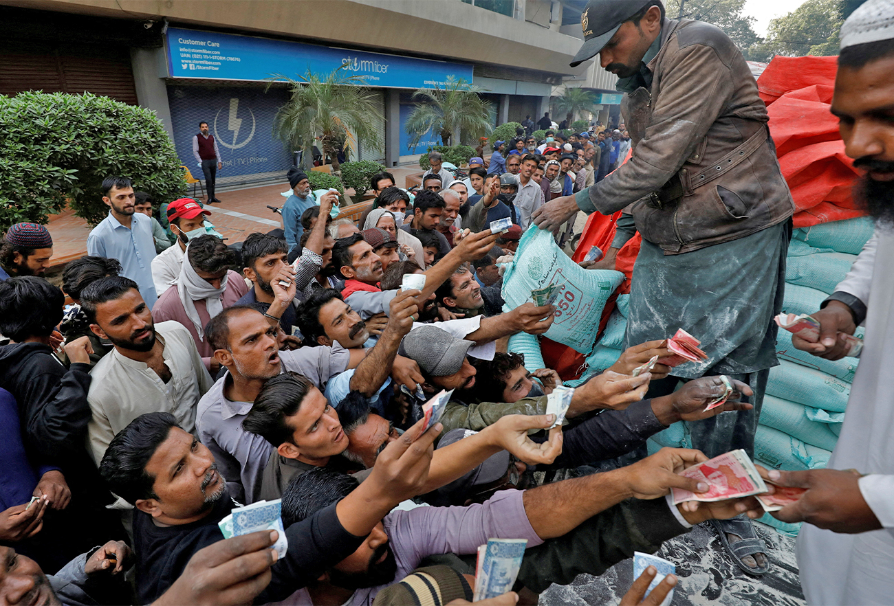 Men reach out to buy subsidised flour sacks from a truck in Karachi, Pakistan on January 10, 2023. (REUTERS)