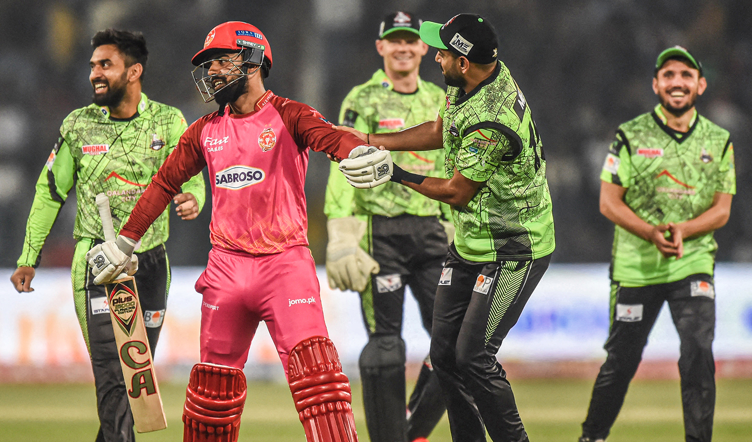 Islamabad United's captain Shadab Khan (2L) walks off the pitch after his dismissal as Lahore Qalandars' cricketers celebrate during the Pakistan Super League (PSL) T20 cricket match at the Gaddafi Cricket Stadium in Lahore on February 27, 2023. (AFP)
