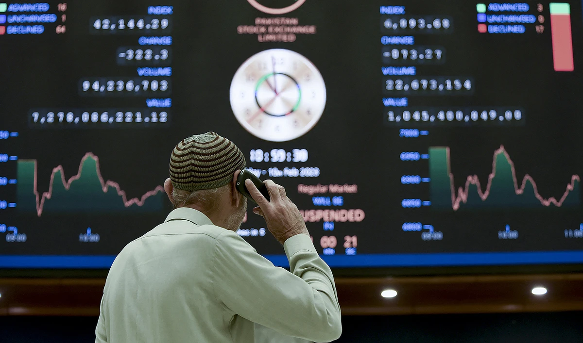 A broker talks on phone as he looks an index board showing the latest share prices at the Pakistan Stock Exchange in Karachi on February 10, 2023. (Photo courtesy: AFP)