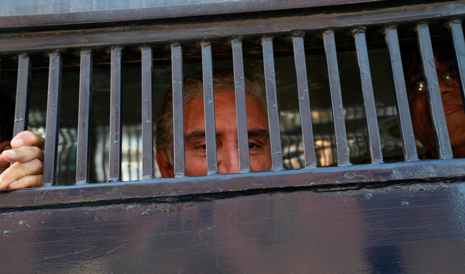 Shah Mahmood Qureshi, left, and Asad Omar, senior leaders of Pakistan's former prime minister Imran Khan's 'Pakistan Tehreek-e-Insaf' party look to media from inside a police van during a rally in Lahore on February 22, 2023. (AP)