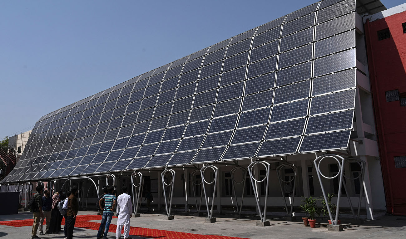 Students look at the facade of a building made with solar panels producing some 148 Kilowatts during its inauguration at the University of Engineering and Technology in Lahore on October 12, 2020. (Photo courtesy: AFP/FILE)
