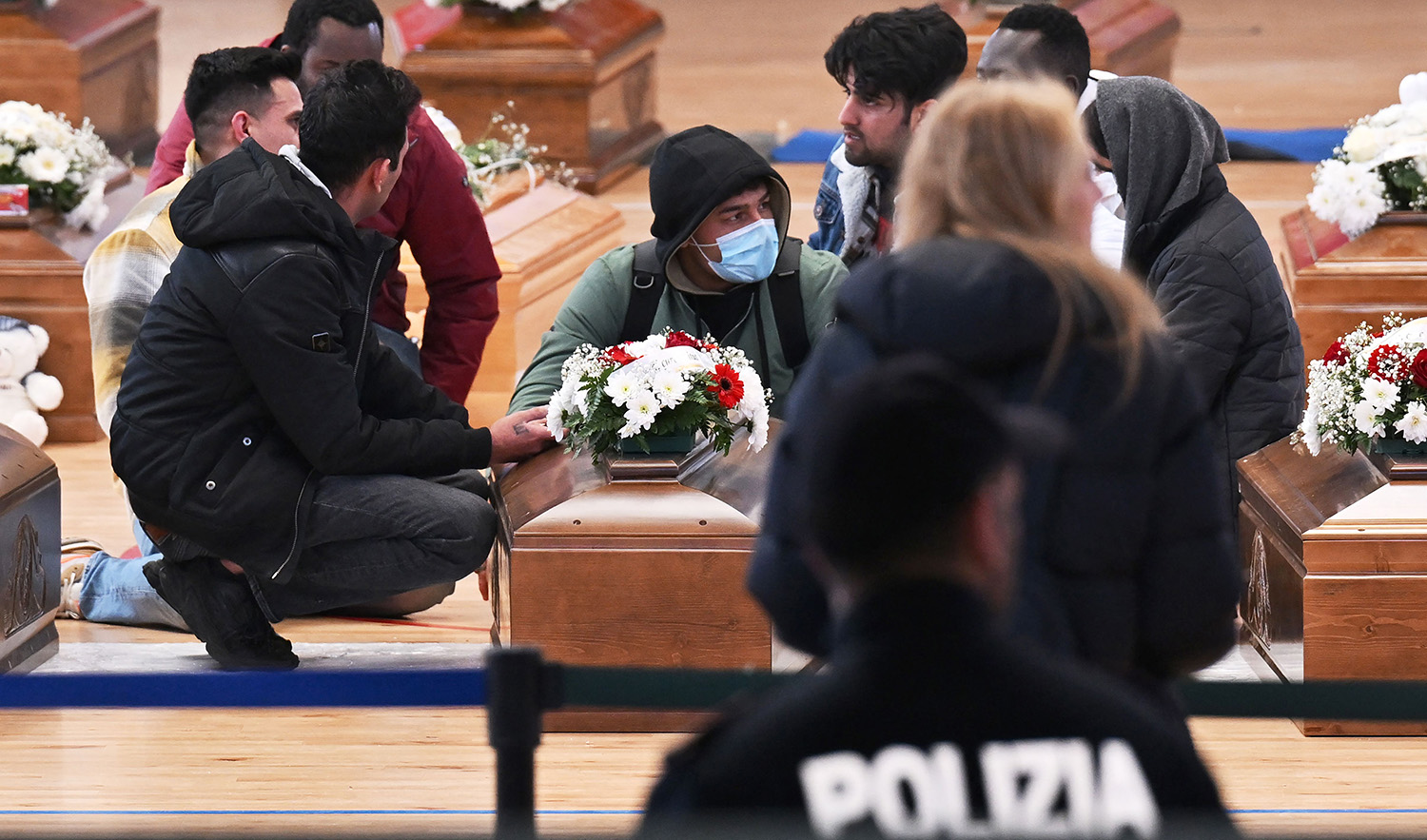 This photo obtained from Italian news agency Ansa and taken on March 1, 2023 shows relatives mourning by one of the coffins of 65 victims of a devastating migrant shipwreck off Italy's southern coast laid out in a sports hall of Crotone on March 01, 2023. (AFP)
