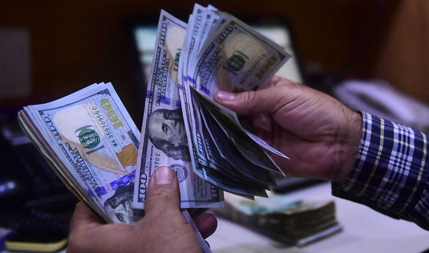 A dealer counts US dollars at a money exchange market in Karachi, Pakistan on March 2, 2023. (AFP)