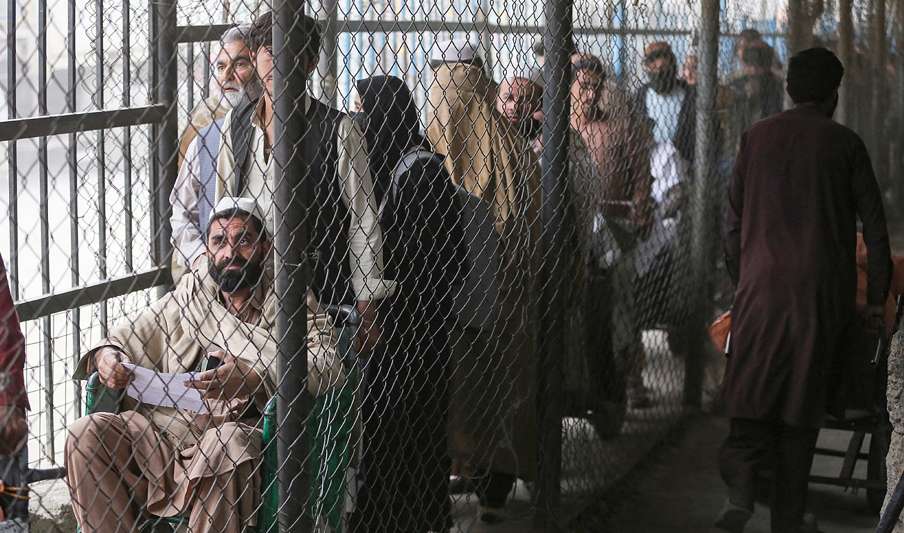Afghan people wait behind a fenced corridor before crossing into Pakistan at the zero point Torkham border crossing between Afghanistan and Pakistan, in Nangarhar province on February 25, 2023. (Photo courtesy: AFP/File)