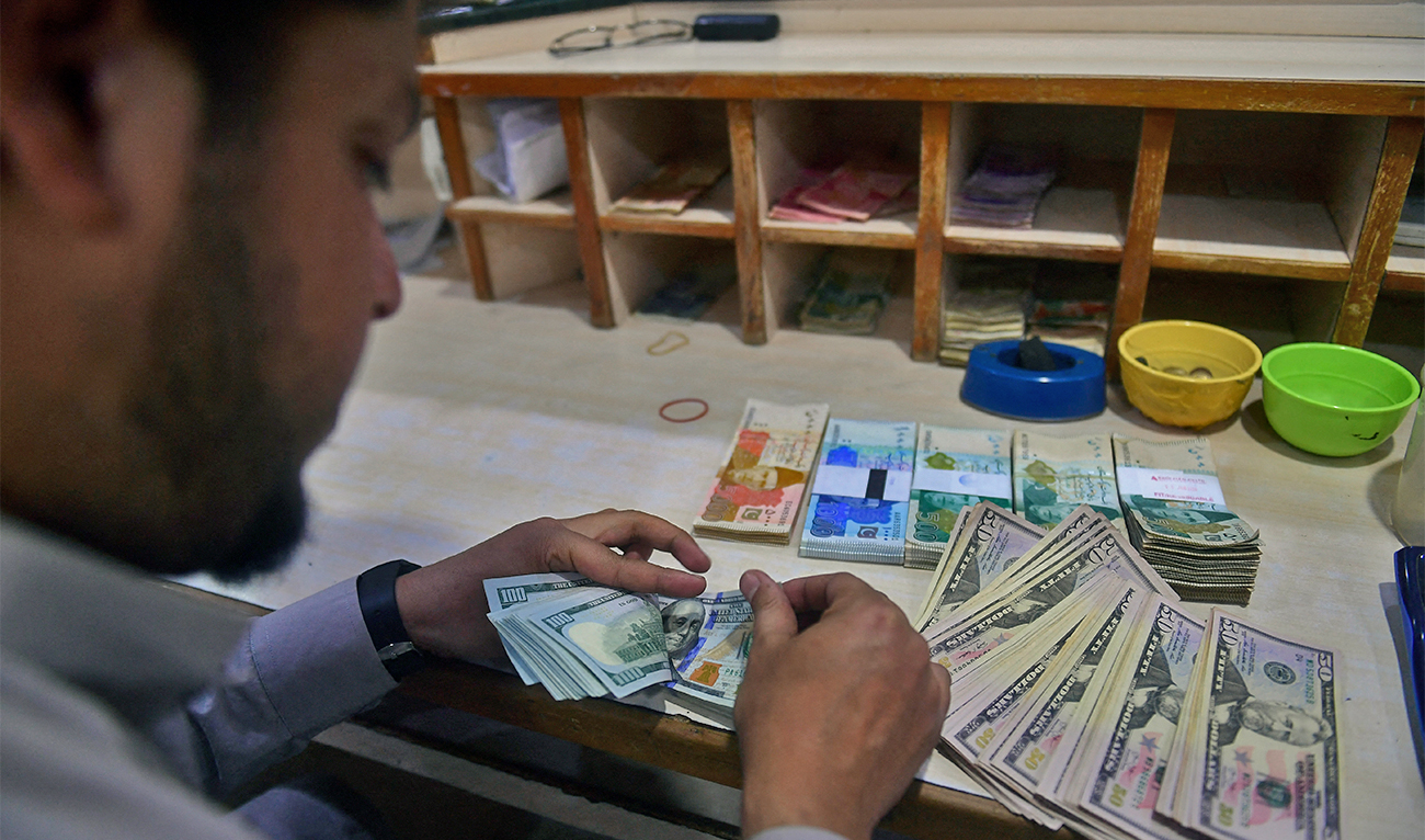 A dealer counts US dollars at a money exchange market in Karachi on January 26, 2023. (AFP/File)