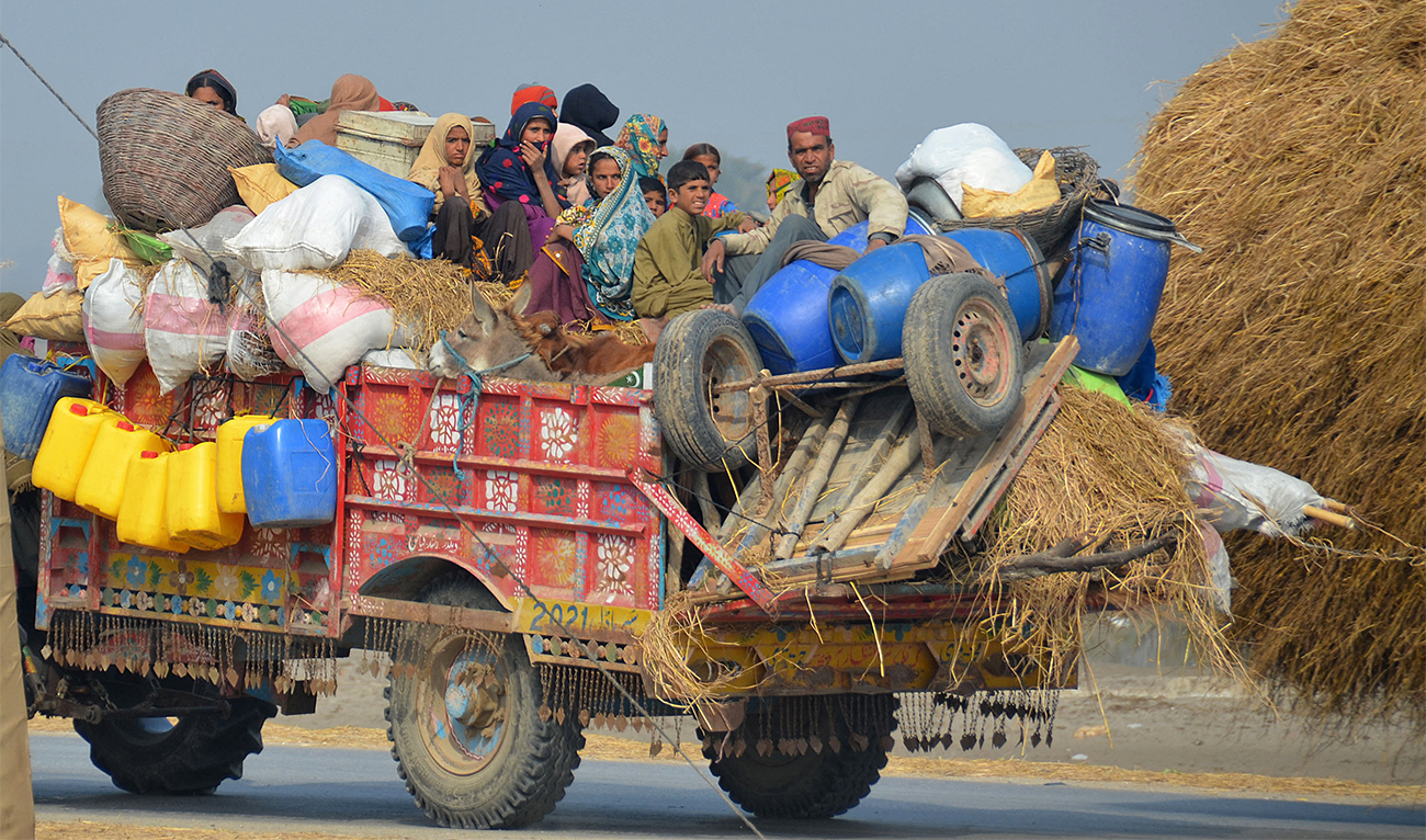 Internally displaced flood-affected people travel on a tractor trolly with their belongings near a makeshift camp in the flood-hit area of Dera Allah Yar in Jaffarabad district of Pakistan's Balochistan province on January 9, 2023. (AFP)