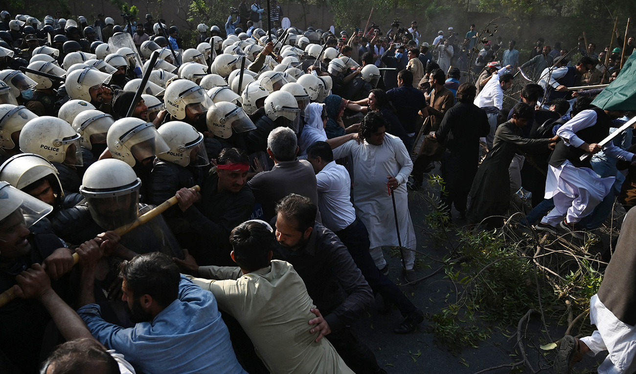 Riot police try to pushback supporters (R) of former prime minister Imran Khan gathered outside Khan's house to prevent officers from arresting him, in Lahore on March 14, 2023. (Photo courtesy: AFP)