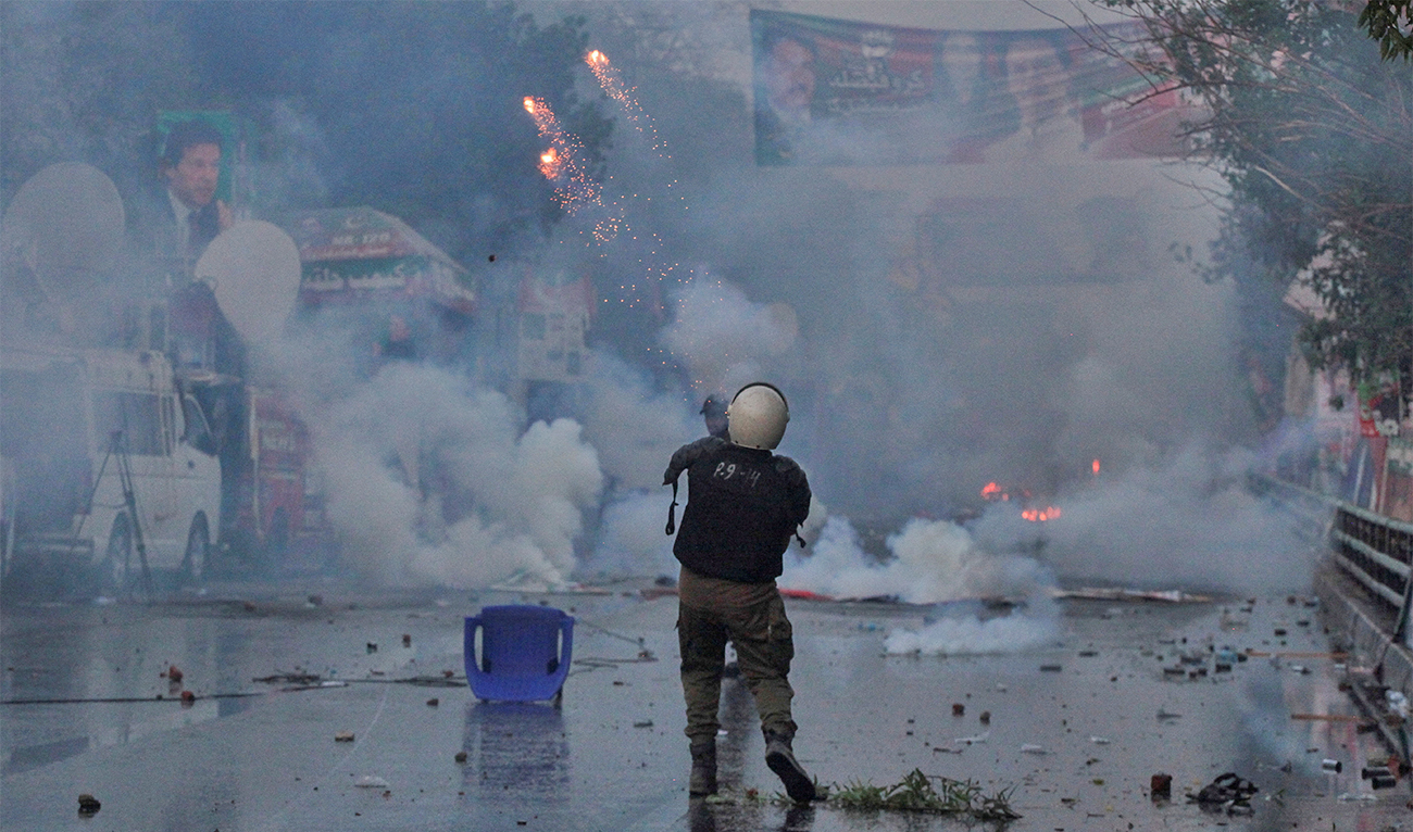 A police officer fires a tear gas shell to disperse the supporters of former Pakistani Prime Minister Imran Khan, during clashes ahead of Khan's possible arrest outside his home, in Lahore, Pakistan, on March 14, 2023. (REUTERS)