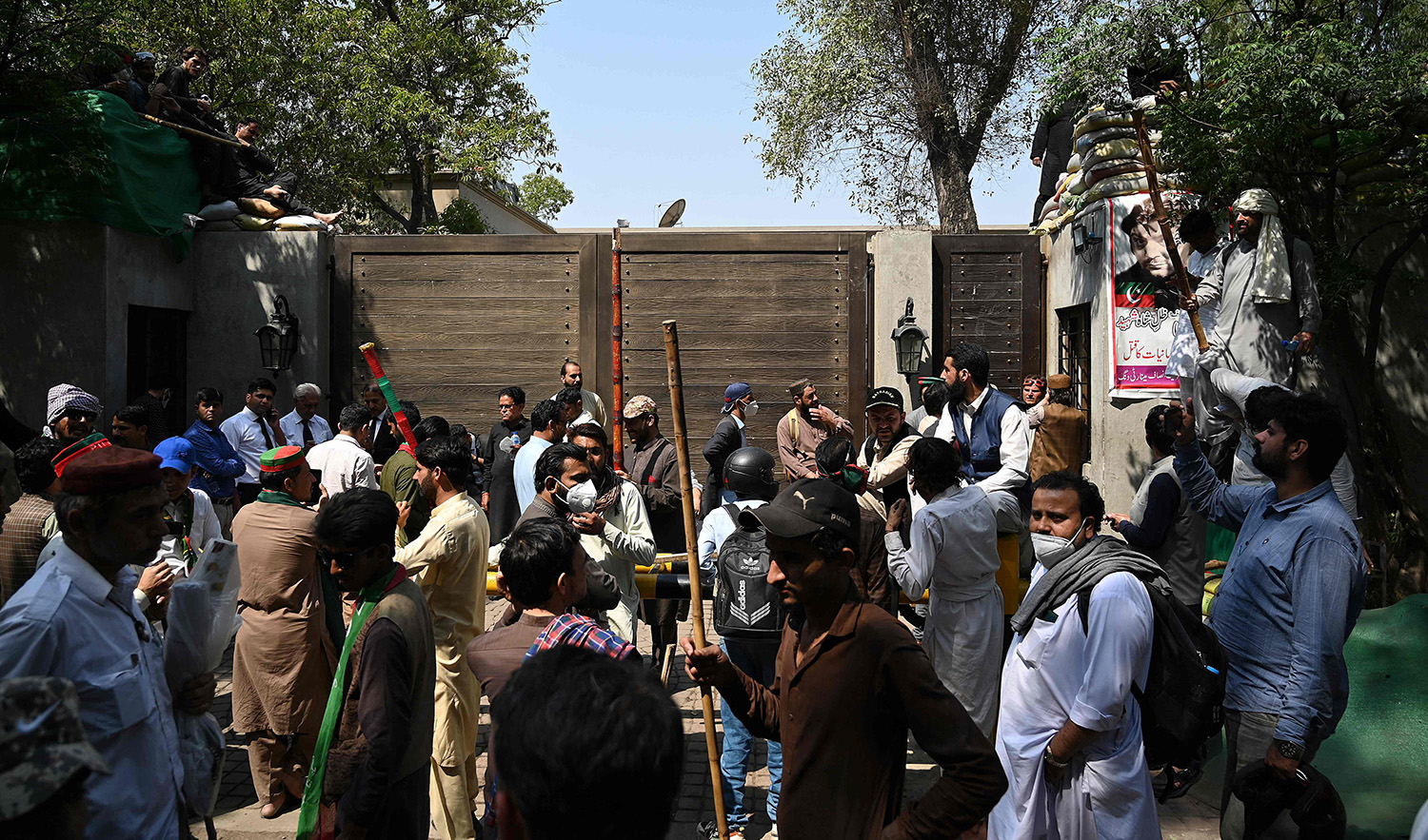 Supporters of former Pakistan's prime minister Imran Khan hold bamboos gather outside Khan's residence in Lahore on March 16, 2023. (AFP)