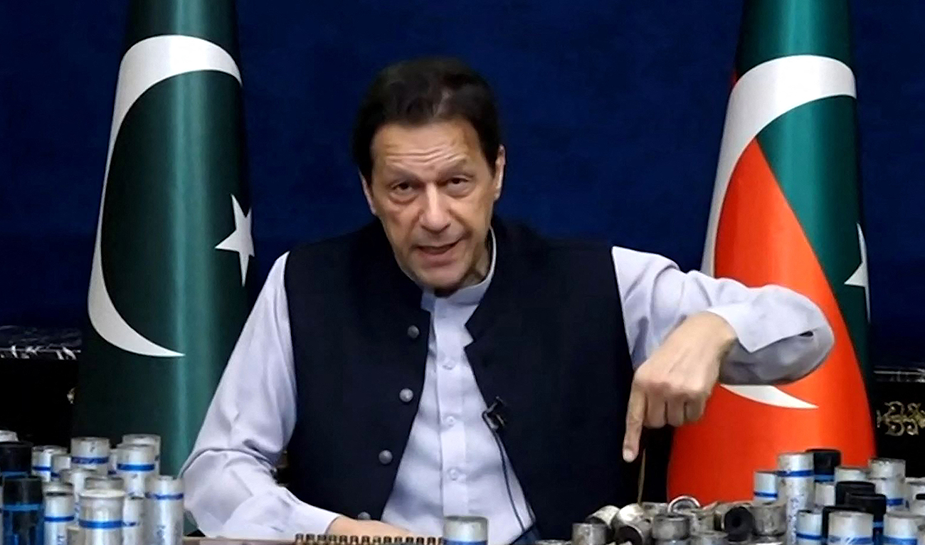This screengrab from Pakistan Tehreek-e-Insaf via AFPTV taken on March 15, 2023 shows former Pakistan prime minister Imran Khan issuing a video statement with a display of spent teargas canisters that he claims were fired into his home in Lahore. (AFP/FILE)