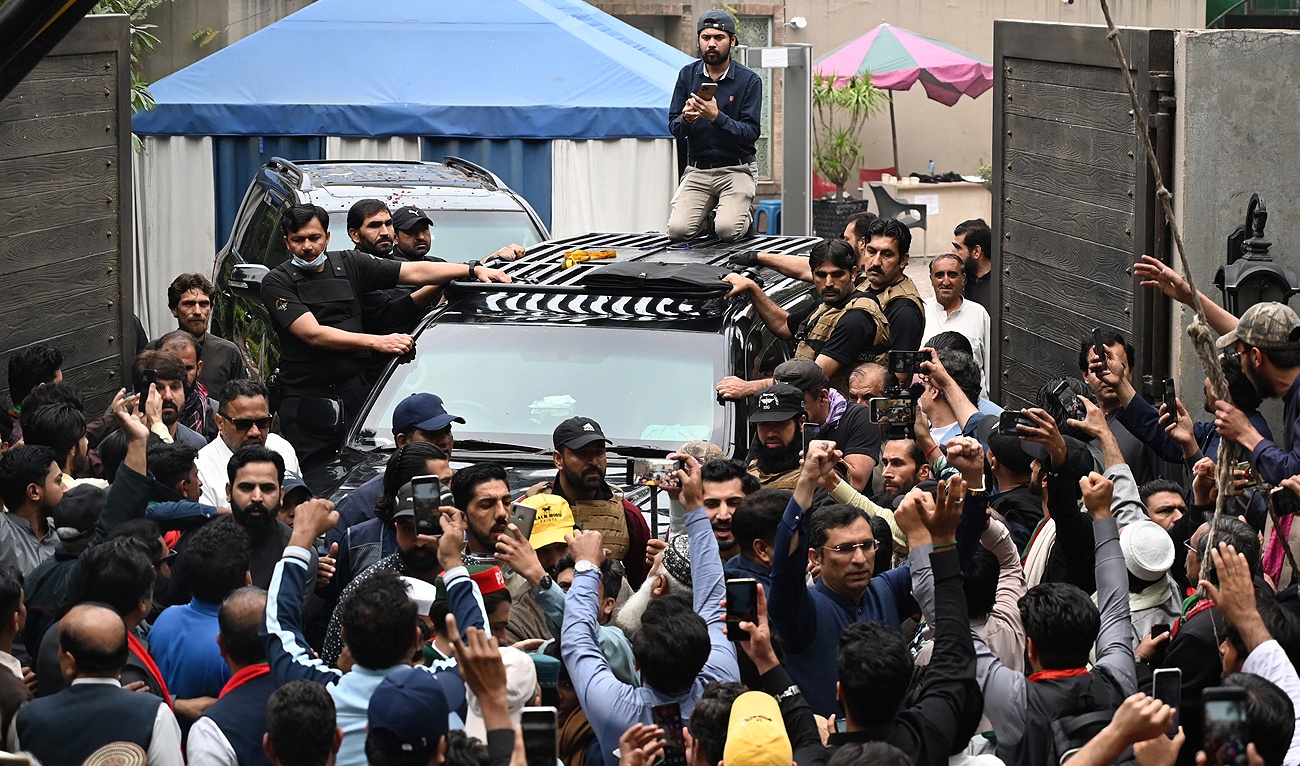 Supporters of former Pakistan's Prime Minister Imran Khan gather around his car as he leaves his residence in Lahore on March 18, 2023, on his way to appear in a court in Islamabad. (Photo courtesy: AFP)