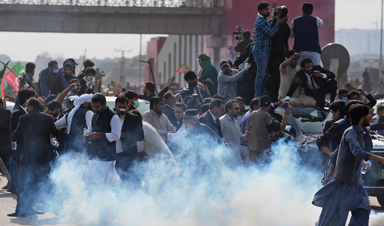 Supporters of former Prime Minister Imran Khan run for cover after police fire tear gas shell to disperse them during clashes, in Islamabad, Pakistan, Saturday, March 18, 2023. (Photo courtesy: AP)