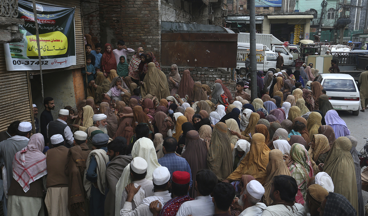 People wait their turn to get a free sack of wheat flour at a distribution point, in Peshawar, Pakistan, on March 23, 2023. (AP)