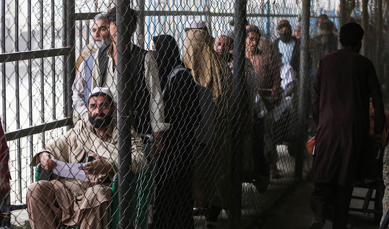 In this file photo, taken on February 25, 2023, Afghan people wait behind a fenced corridor before crossing into Pakistan at the zero point Torkham border crossing between Afghanistan and Pakistan, in Nangarhar province. (Photo courtesy: AFP/File)