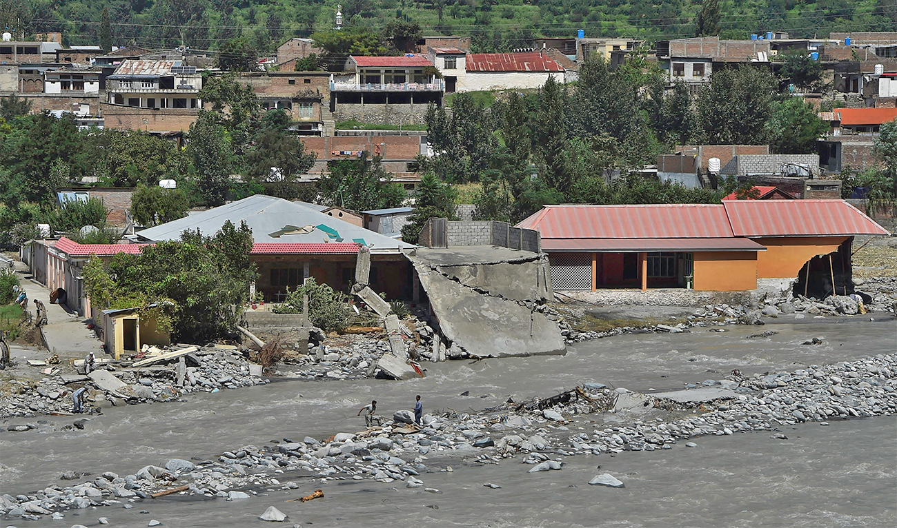Local residents stand near houses damaged along the banks of the Swat River after heavy rains in Madyan area of Swat valley, Khyber Pakhtunkhwa province, on August 31, 2022. (AFP/File)